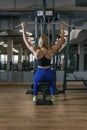 Young slender woman trains in the gym. Healthy and strong girl. Back view. Upper block thrust