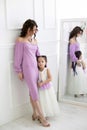 Vertical portrait of a slender young mother and her five year old daughter against the background of the mirror Royalty Free Stock Photo