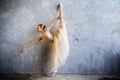 Young ballerina in a golden colored dancing costume is posing in a loft studio Royalty Free Stock Photo