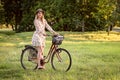 Young, slim, blonde woman on bicycle against defocused park landscape. Autumn color shade Royalty Free Stock Photo