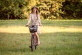 Young, slim, blonde woman on bicycle against defocused park landscape. Autumn color shade Royalty Free Stock Photo