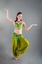 Young slim brunette woman in green belly dancer costume poses at camera Royalty Free Stock Photo