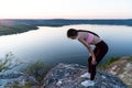 Young slim brunette woman in sportswear leaned on her legs, tired after a long climb to the mountains top