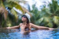 Young slim brunette woman sunbathe in tropical swimming pool Royalty Free Stock Photo