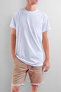 Young slim caucasian man in a blank T-shirt on a white studio background