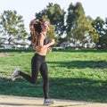 Slim caucasian woman running in a green urban park