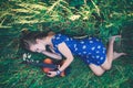 Young slim fair-skinned girl blonde beautiful lies in tall grass. Girl in a blue short tight dress with a print of daisies. A Royalty Free Stock Photo