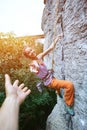 Young slim female rock climber climbing on the cliff and getting help Royalty Free Stock Photo