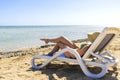 Young slim female woman in bikini,hat enjoy relaxing chilling,sunbathing on loungers on sand sea,ocean beach,coast in luxury