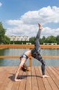 Young slim girl in grey sport wear doing yoga on the bridge. Flexible young girl with red hair.