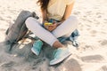 Young slim girl sitting on the beach in jeans and a yellow T-shirt and listening to music with headphones and mobile phone Royalty Free Stock Photo