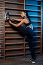 Young slim gymnast woman in sports clothing stretching on the wall bars in neon lights. Flexible gymnastic exercise. Royalty Free Stock Photo