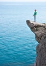 Young slim lonely woman standing at the edge of mountain cliff Royalty Free Stock Photo