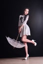 Young slim model in light summer dress with a filigree umbrella posing in studio. Black background Royalty Free Stock Photo