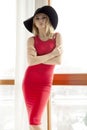 Young slim woman in red dress against the window Royalty Free Stock Photo