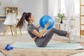 Young slim woman doing fit exercises lying on yoga mat in the living room at home using fit ball. Royalty Free Stock Photo