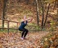 Young slim woman doing fitness exercise stretching in autumn forest park background, active healthy lifestyle outdoors Royalty Free Stock Photo
