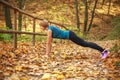 Young slim woman doing fitness exercise stretching in autumn forest park, sport and healthy lifestyle Royalty Free Stock Photo