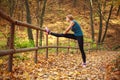 Young slim woman doing fitness exercise stretching in autumn forest park, sport and healthy lifestyle Royalty Free Stock Photo