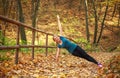 Young slim woman doing fitness exercise stretching in autumn forest park, sport and healthy lifestyle Royalty Free Stock Photo