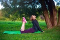 Young slim woman doing yoga and stretching, fitness exercises in sunny green forest  park Royalty Free Stock Photo