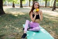 Young slim woman having snack after working out outdoors in the park. Sitting on the grass, eating juicy apple on fresh air Royalty Free Stock Photo