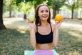 Young slim woman having snack after working out outdoors in the park. Sitting on the grass, eating juicy apple on fresh air Royalty Free Stock Photo