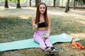 Young slim woman having snack after working out outdoors in the park. Sitting on the grass, eating juicy apple on fresh air Royalty Free Stock Photo