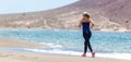 Fitness girl jogging at ocean beach on sunny day Royalty Free Stock Photo