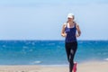 Fitness girl jogging at ocean beach on sunny day Royalty Free Stock Photo