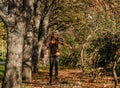 A young slim woman jumps in the park between the trees and looks joyful. Royalty Free Stock Photo