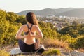 Young slim woman meditating in the Park. The concept of yoga, sports and meditation. Mountain view and settlement in the