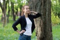 Young slim woman rests on a tree trunk, she looks straight ahead with a dreamy look