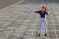 Young slim woman in sportswear doing squats exercise with rubber band on a black coated stadium track