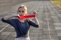 Young slim woman in sportswear doing squats exercise with rubber band on a black coated stadium track