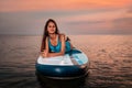 A young slim woman in swimsuit lies on a sup board. Sunset in the background. Copy space. Concept of sport and summer Royalty Free Stock Photo