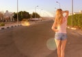 Young slim woman walking barefoot on a long deserted road in old town. Beautiful sunny weather Royalty Free Stock Photo