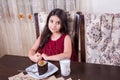 Young small beautiful middle eastern child girl with chocolate cake with pineapple, strawberry, and milk with red dress and dark Royalty Free Stock Photo