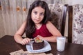 Young small beautiful middle eastern child girl with chocolate cake with pineapple, strawberry, and milk with red dress and dark Royalty Free Stock Photo