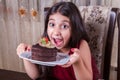 Young small beautiful middle eastern child girl with chocolate cake with pineapple, strawberry, and milk with red dress and dark Royalty Free Stock Photo