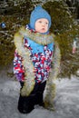 Young small boy walking and having photo shoot in park or forest full of snow in a cold winter day. Male child having Royalty Free Stock Photo