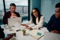 Young smart african american businesswoman showing a graph to her multiethnic male colleagues in a modern office - Royalty Free Stock Photo