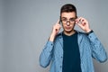 Young smart guy talks on phone, adjusting glasses