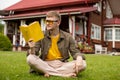 Young smart man relaxing in nature reading book sitting on grass outdoors Royalty Free Stock Photo