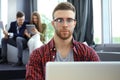Young smart people are using gadgets while working hard in the modern office. Young man working on his laptop. Royalty Free Stock Photo