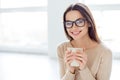 Young smart successful woman in glasses having break, holding cup and drink coffe