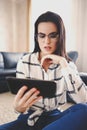 Young smart woman in glasses reading at home on tablet Royalty Free Stock Photo