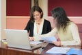 Young smartly dressed lady helps another young lady to work with documents, fill forms and sign Royalty Free Stock Photo