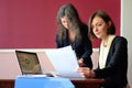 Young smartly dressed lady helps another young lady to work with documents, fill forms and sign Royalty Free Stock Photo