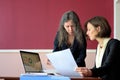 Young smartly dressed lady helps another young lady to work with documents, fill forms and sign